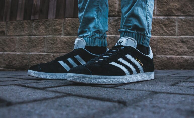 person wearing pair of black and white adidas gazelle